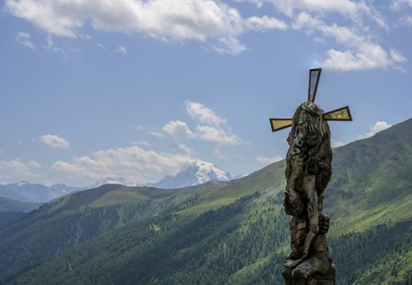 Wooden sculpture Four-man column behind it the Ortler