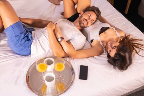 A loving couple in pajamas having breakfast in the hotel bed