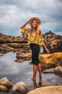 Girl in a floral shirt and black shorts in a natural landscape by the sea at sunset