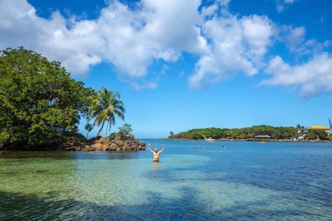 A young man entering the Caribbean Sea at West End Beach on Roatan Island. Honduras