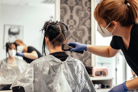 Hairdresser with mask shaving with razor. Reopening with security measures of Hairdressers in the Covid-19 pandemic