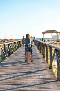 A young mother walking on the walkway of the Bateles beach in Conil de la Frontera