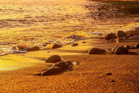 Stones in the water on the beach at sunset in Puerto de Tazacorte on the island of La Palma