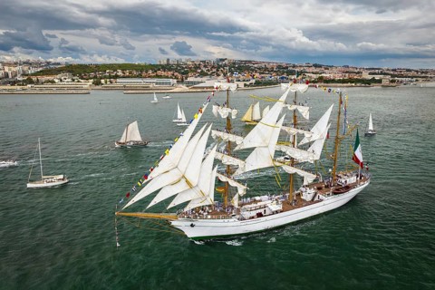 Aerial drone view of tall ships with sails sailing in Tagus river towards the Atlantic ocean in Lisbon