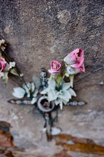 Artificial roses behind a cross on a weathered wall on a grave in a cemetery