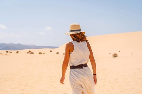 A young tourist wearing a hat walking along the sand on the beaches of the Corralejo Natural Park