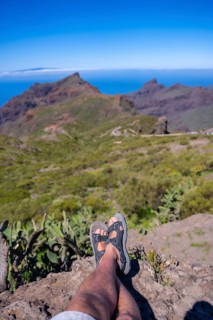 A young man sitting looking at the mountain town of Masca in the north of Tenerife