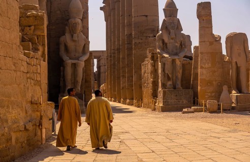 Two local men visiting the Egyptian Temple of Luxor and its precious column