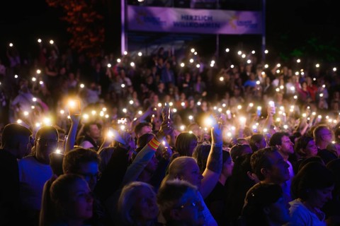Crowd with mobile phone lights at Live Klostersommer Festival in Historic Monastery