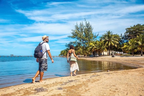 Two young people walking along the beach of Sandy Bay on Roatan Island. Honduras
