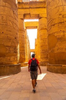A young man strolling between the hieroglyphic columns of the Temple of Karnak