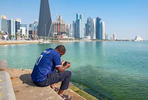 Man sits on steps of Corniche with skyscrapers in background