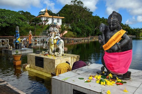 Right Hindu deity statue figure sculpture of goddess deity of Lord Muruga left beside Dattatreya triune figure Brahma Vishnu beside Lord Shiva in background woman Shakti of Shiva Hindu mother goddess ...