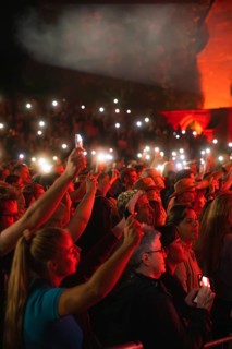 Crowd with mobile phone lights at Live Klostersommer Festival in Historic Monastery