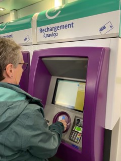 Elderly woman charging her smart card at a charging station for the Navigo Easy Travel Card