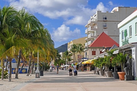 Tourists walking on boulevard with palm trees along the beach in capital city Philipsburg of the Dutch island part of Sint Maarten in the Caribbean