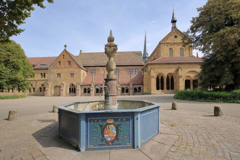 Romanesque monastery church and fountain with coat of arms of Wuerttemberg Duke Ludwig