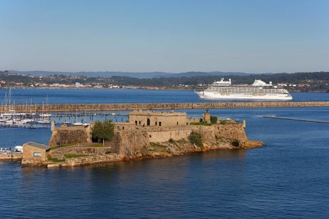 Historic fortress Castle San Anton at the harbour entrance and cruise ship Seven Seas Splendor leaving port