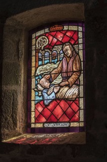 Stained-glass window showing St Samson curing man from leprosy in the Saint-Samson chapel