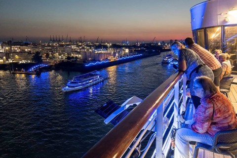 Passengers sit on the Lido Deck of the cruise ship Vasco da Gama and watch the Blue Port light art event in the harbour