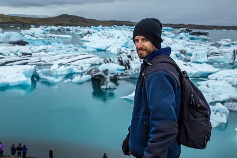 A young man with a backpack looking at the Jokulsarlon Ice Lake in the golden circle of southern Iceland