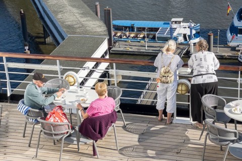 Passengers sitting at a table on the Lido Deck of the cruise ship Vasco da Gama moored at the Ueberseebruecke in the Port of Hamburg