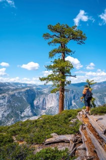 A young man with a brown jacket in Sentinel Dome looking at Upper Yosemite Fall