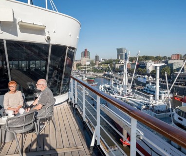 Passengers sitting at a table on the Lido Deck of the cruise ship Vasco da Gama moored at the Ueberseebruecke in the Port of Hamburg