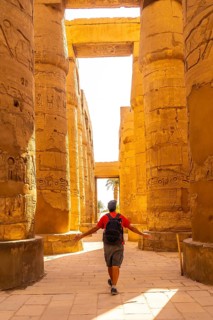 A young man strolling between the hieroglyphic columns of the Temple of Karnak