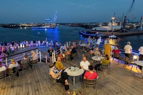 Passengers sit on the Lido Deck of the cruise ship Vasco da Gama and watch the Blue Port light art event in the Port of Hamburg in the evening