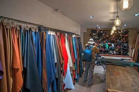 Tourist taking pictures of the leather shelves in a saddlery with permission