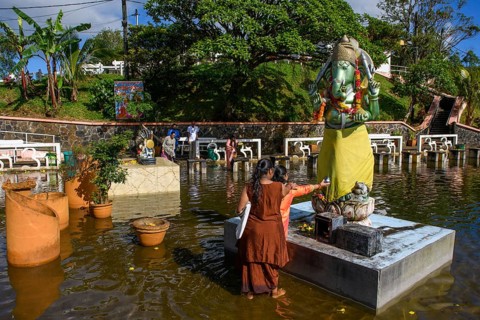Woman in traditional Indian dress standing in Sacred Lake offering sacrifice to God deity in elephant shape figure of elephant elephant god Ganesha at religious site largest Hindu sanctuary sanctuary ...