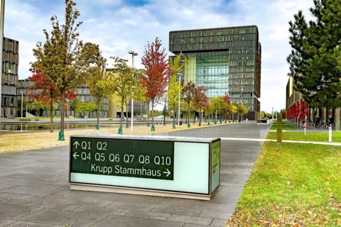 View of headquarters in the background in the form of cube of steel giant company of steel production manufacturer of steel thyssenkrupp Thyssen Krupp in the foreground signpost and reference to ances...