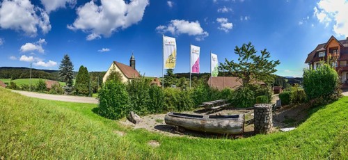 Rest area for hikers with flags and the pilgrimage church of Oberbiederbach in Biederbach