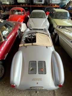 Porsche 550 Spyder Replica stands for reconditioning in large hall behind it other vintage VW Beetle Golf