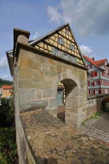 Historic town wall with archway and half-timbered house