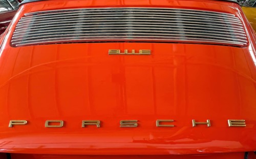 Rear of classic car Porsche 911 E from the 60s in orange colour with typical radiator grille
