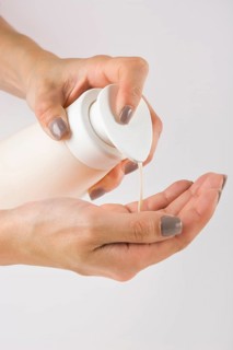 Close up female hands using hand sanitizer gel pump dispenser