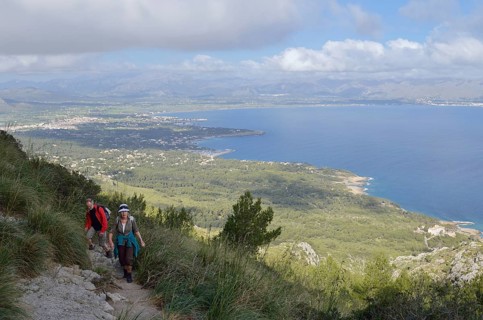 Hikers on the peninsula of La Victoria and view of the bay of Pollenca