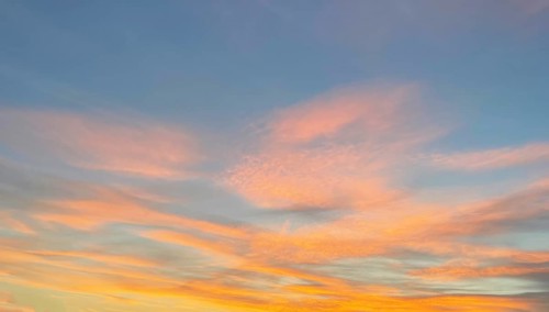 Orange reddish clouds Veil clouds Cirrostratus at the bluish evening sky at dusk