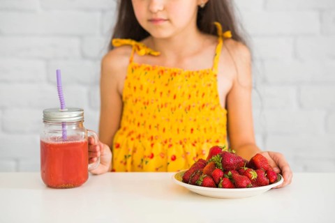 Close up girl holding plate strawberries smoothies jar