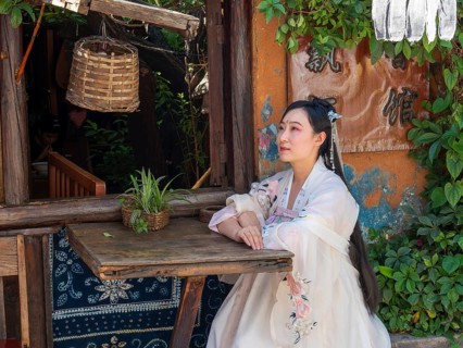 Woman in Chinese nostalgia with old luxurious white dress in front of old house