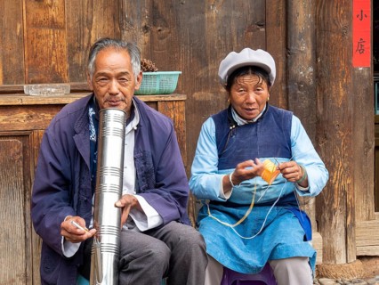 Old Chinese couple sitting in front of wooden house