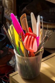 Plastic conatiner filled with colourful utensils for sale inside second hand goods and chattels store