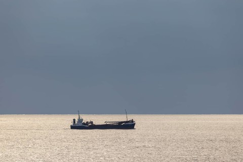 Dark clouds and sunlight over the North Sea plus freighter