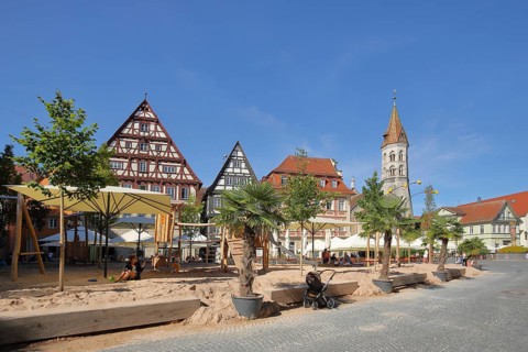 Sandy beach beach and children's playground with neo-Romanesque St. John's Church on the market square