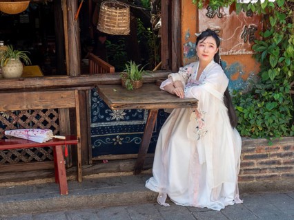 Woman in Chinese nostalgia with old luxurious white dress in front of old house
