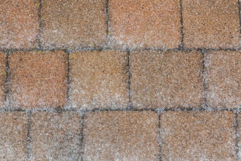 Nuanced tan and brownish paving stones covered with layer of ice