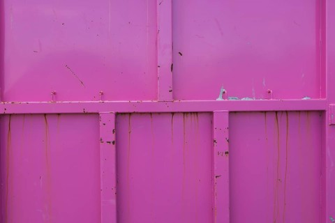 Pink painted metal container with rust stains