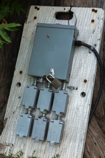 Locked grey metal electrical distribution box and outlets for plugging in extension cords